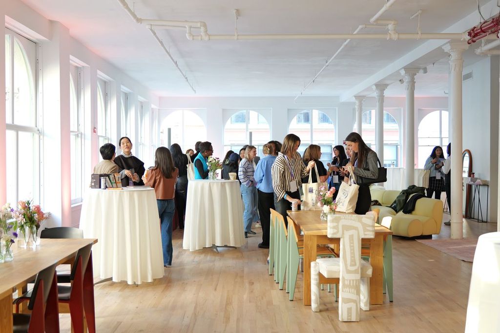 Guests mingling around cocktail tables at a corporate summit in a sunlit loft