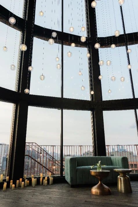 A glass-walled event space with lounge seating at dusk