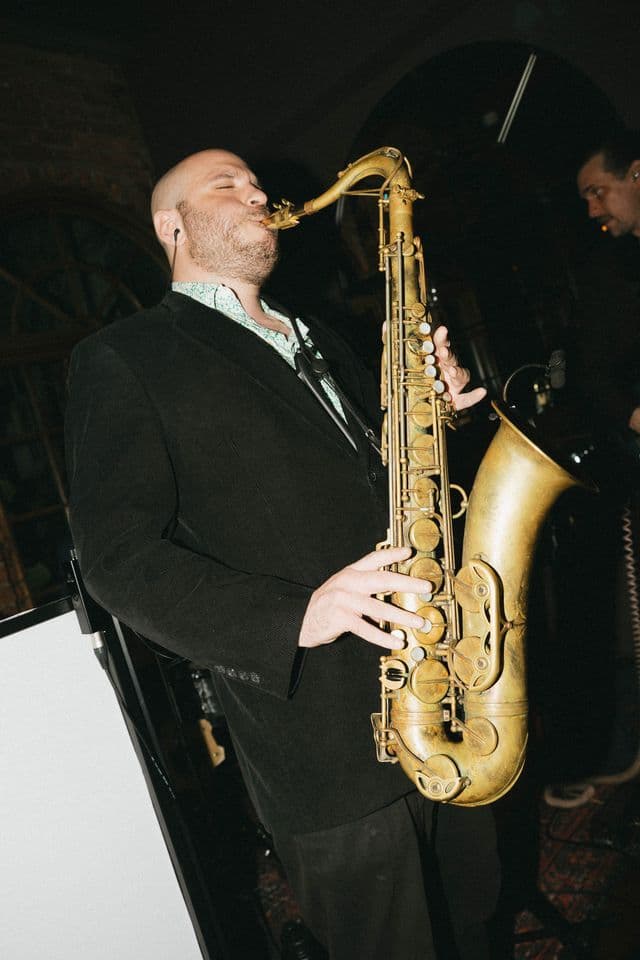 A saxophonist playing a set at an evening reception