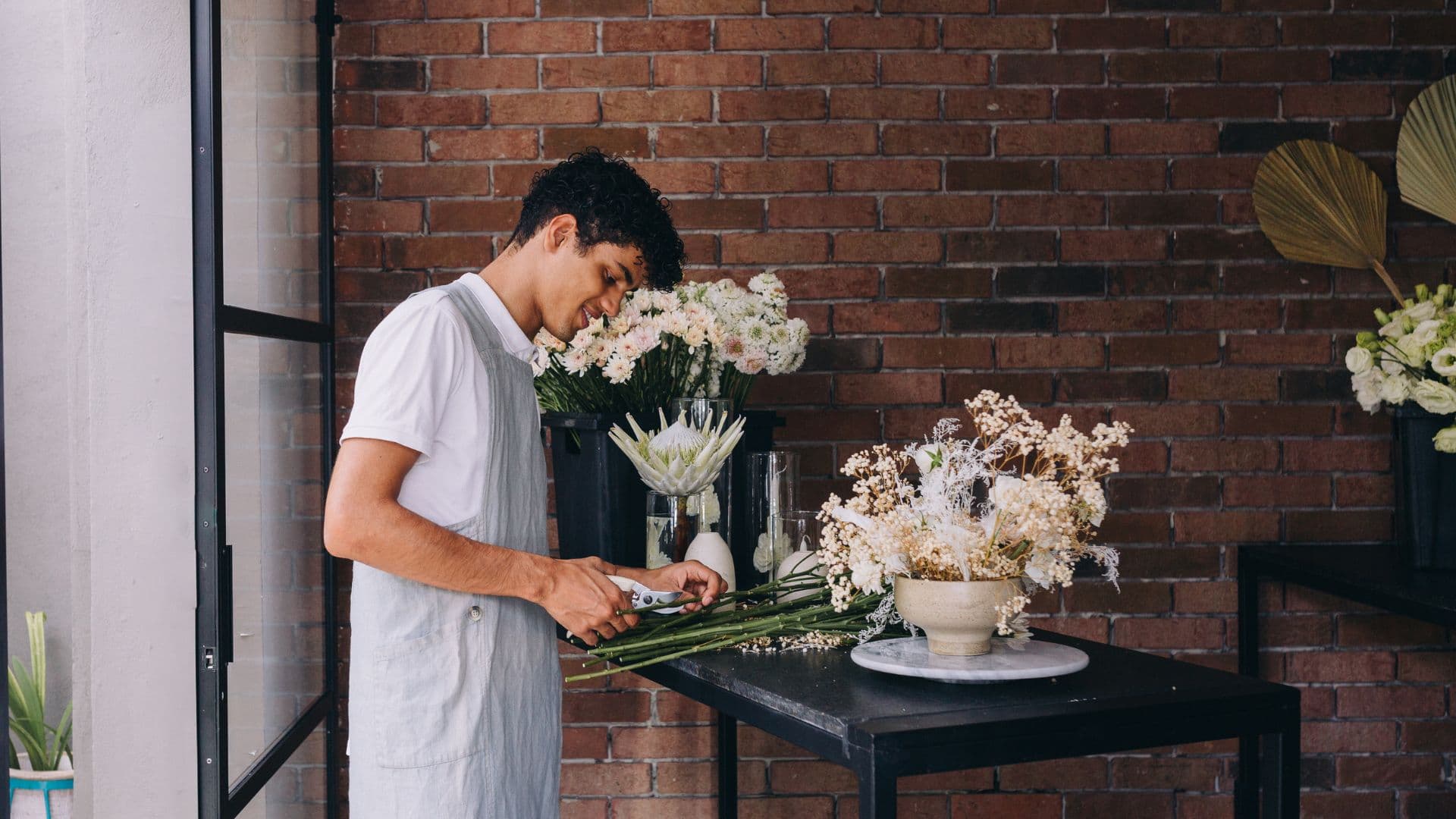 A florist arranging stems in their studio
