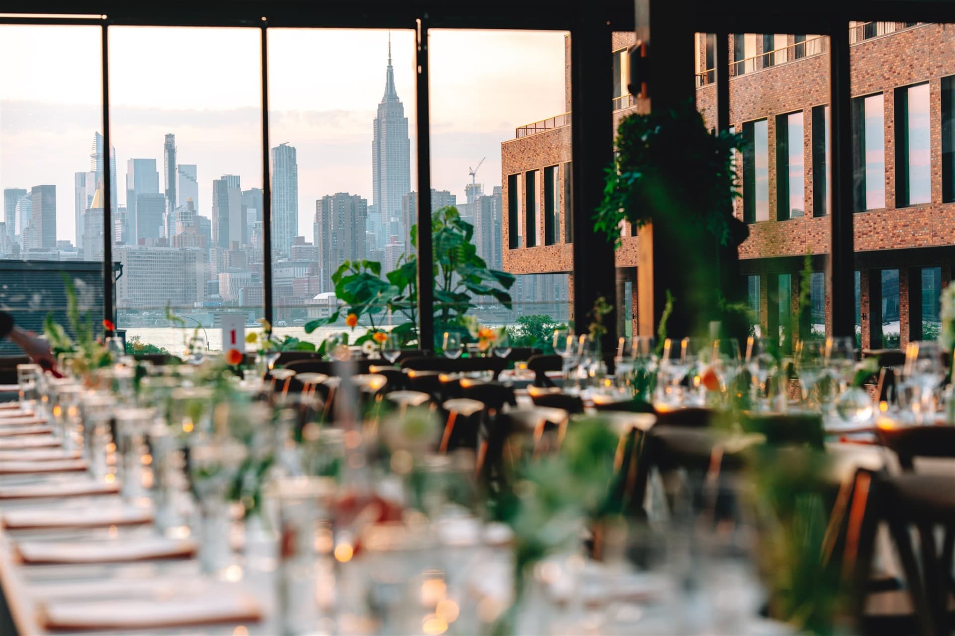 Rooftop reception table set with greenery and candlelight, overlooking the New York City skyline at sunset